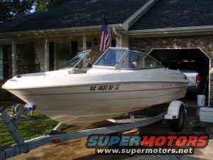 Boat on a trailer in front of a house. License plate reads SC 4437 BF