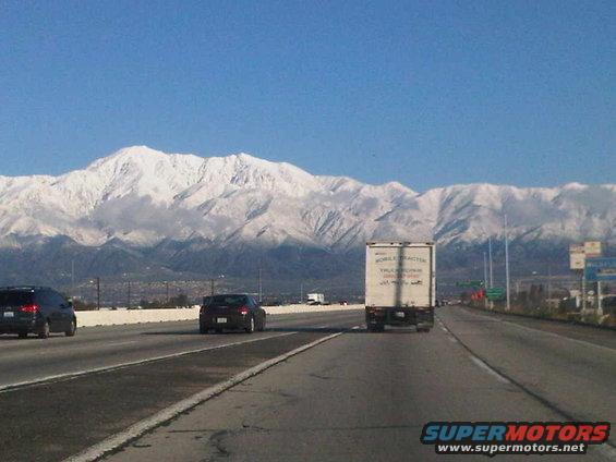 Highway driving with snow-covered mountains in the background and several vehicles on the road