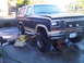 1986 Ford Bronco - This two-tone Ford Bronco is elevated on jack stands, suggesting it is undergoing maintenance or repair.