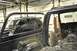 1996 Ford Bronco - A black SUV is visible in the background of a garage, partially obscured by the interior of another vehicle undergoing modifications.