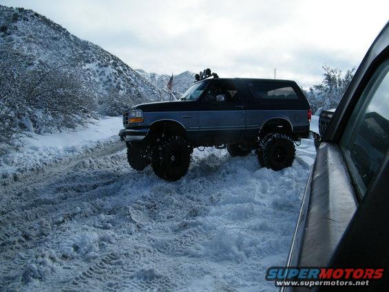 Lifted Ford Bronco driving on a snowy mountain road