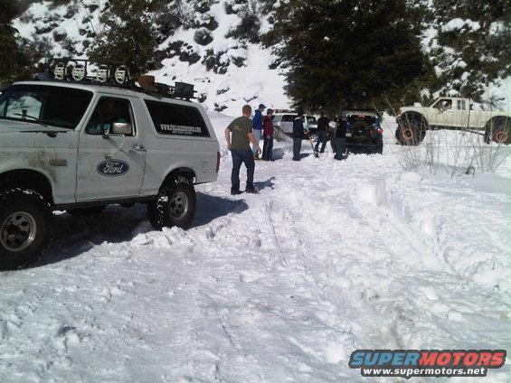 White Ford Bronco with off-road tires and roof lights in snow