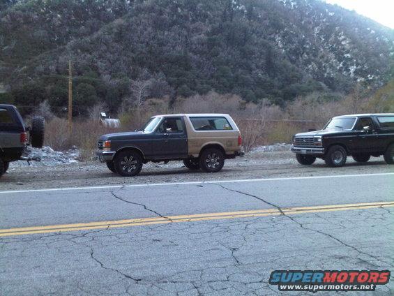 Two-tone Ford Bronco parked on roadside with a black Bronco behind it