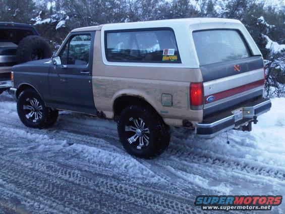 1986 Ford Bronco in snow, rear 3/4 view, two-tone paint
