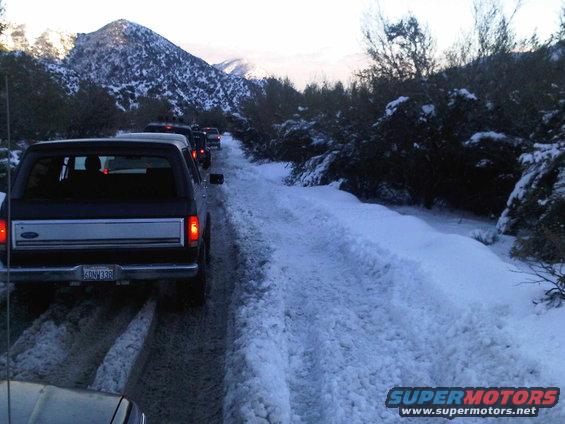 Line of SUVs driving on a snowy road in the mountains. License plate reads 6DNW338