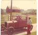 1927 Dodge 1500 - A vintage maroon coupe, likely a 1927 Dodge, sits on a dirt road with a barn and fields in the background.