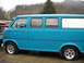 1982 Ford Bronco - A blue van with a flat front tire is parked next to a red truck.