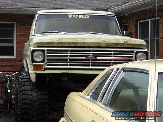 Front view of a lifted 1970 Ford truck with large tires and a "FORD" windshield banner