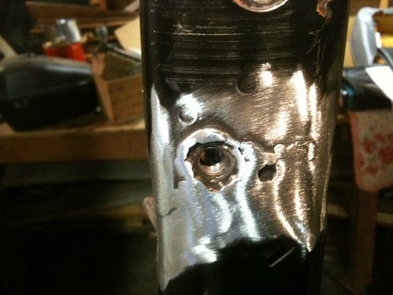 Metal bracket with a damaged threaded hole and surrounding metalwork