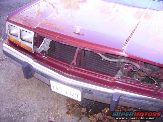 car's front end is smashed in, grille is gone, radiator is exposed, hood is dented