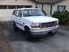 1996 Ford Bronco - This white 1996 Ford Bronco is parked in a driveway in front of a house and garage.
