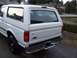 1996 Ford Bronco - This white Ford Bronco, viewed from the rear quarter, features a camper shell and chrome bumper.