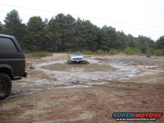 Black Ford Bronco side view, white Ford Bronco stuck in mud pit