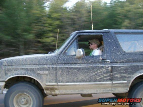 Side view of a muddy 1994 Ford Bronco with a driver wearing sunglasses