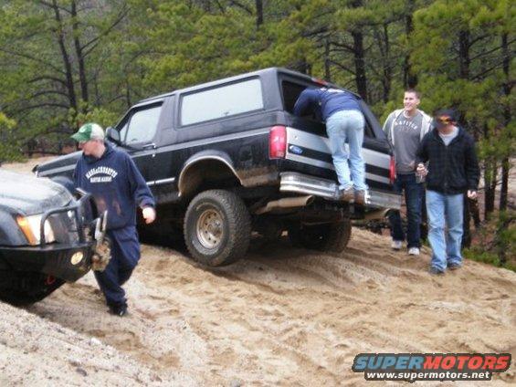 Black 1994 Ford Bronco on a sandy trail with people around it