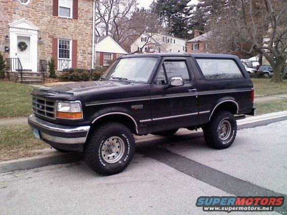 Black Ford Bronco parked on street, house in background