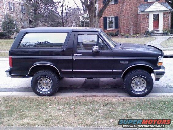 Side view of a black Ford Bronco parked on a street. It has BFGoodrich All-Terrain tires