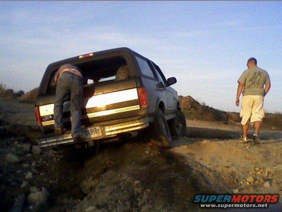 1994 Ford Bronco on a dirt trail with a person climbing into the back