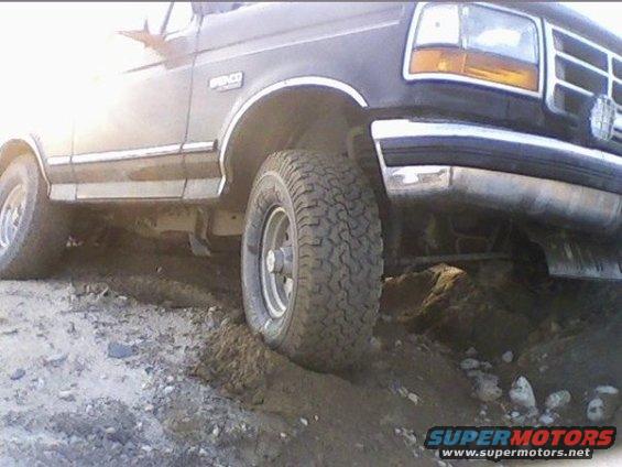 Black 1994 Ford Bronco on dirt road, front wheel turned