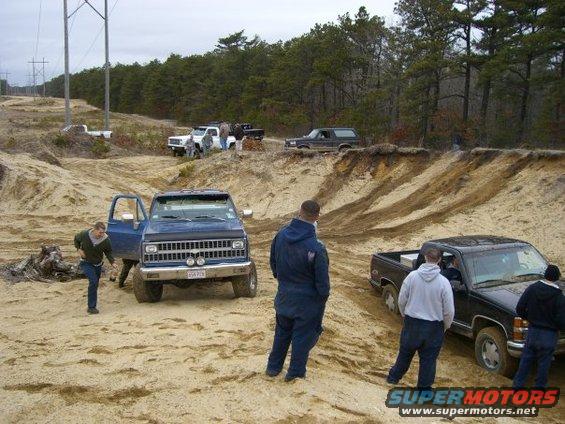 Dark gray Ford Bronco parked on a sandy incline, front 3/4 view