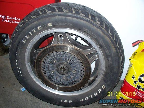 Motorcycle wheel with Dunlop Elite II tire and brake disc. Red cart with 'Off Service' text visible