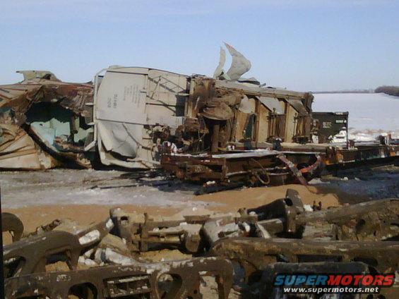 Debris from a train derailment, with damaged train cars and scattered metal parts