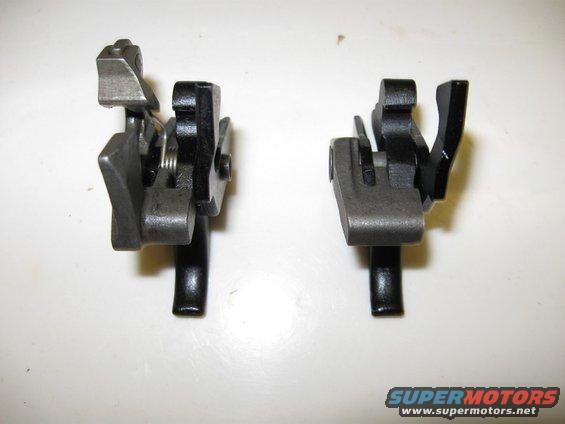 Two black and silver metal mechanical parts with springs and levers, viewed from the front