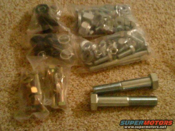 Several plastic bags filled with nuts, bolts, and other hardware, with two large bolts in the foreground