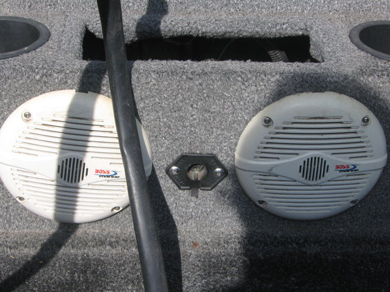 Two white Boss Marine speakers mounted in a gray carpeted boat interior