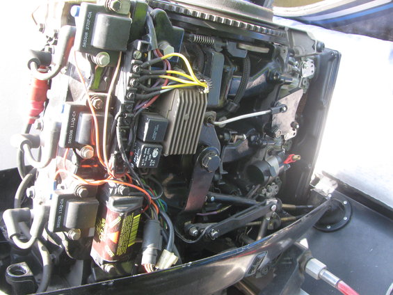 Outboard motor engine with visible wiring, coils, and carburetor