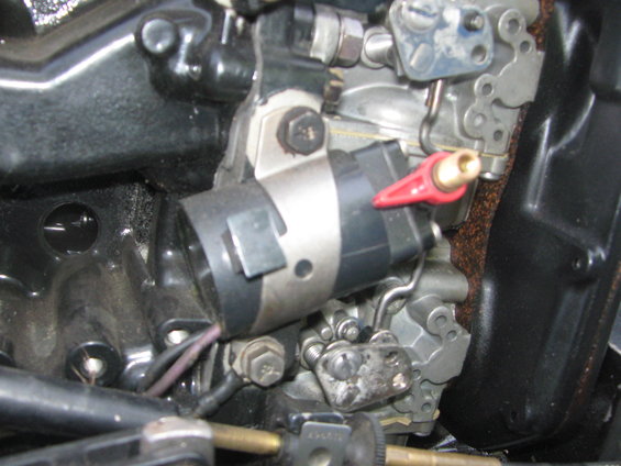 Close-up of a boat motor carburetor with a red lever