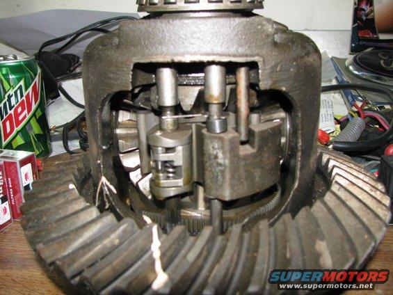 close-up of an open differential gear assembly with gears and springs visible, can of Mountain Dew and cigarette pack nearby