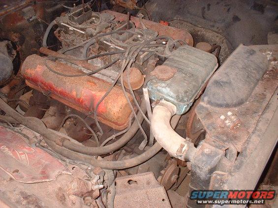 Engine bay with rusty V8 engine, carburetor, and radiator