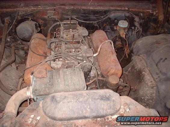 engine bay with V8 engine, dual carburetors, and rusty components