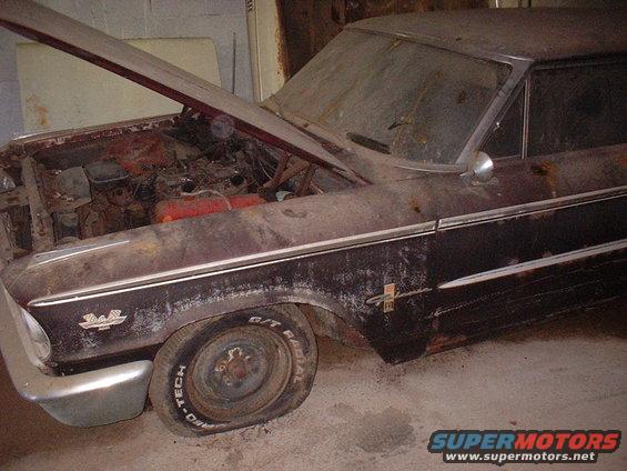 Rusty 1963 Ford Galaxie with hood open, flat tire, and chrome trim
