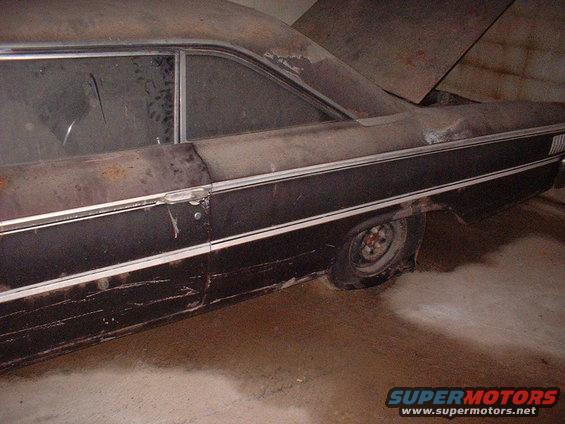 Side view of a rusty 1963 Ford Galaxie sedan with a dark body and chrome trim
