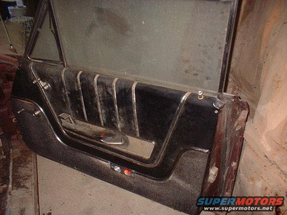 Car door panel with black upholstery and chrome trim. Window crank and door handle visible