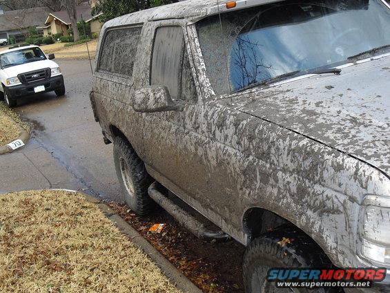 Mud-covered 1992 Ford Bronco, driver's side, parked on a residential street