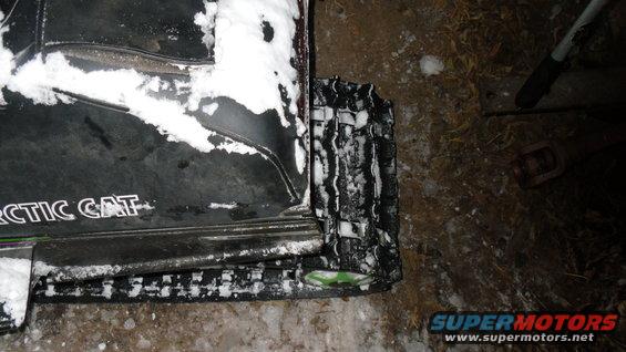 Close-up of Arctic Cat snowmobile track and side panel with snow