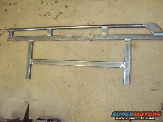 Metal rock sliders with horizontal and vertical bars, welded together, lying on a concrete floor