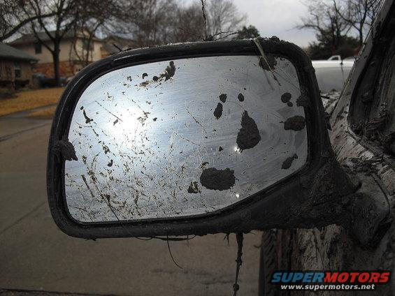 Mud splatters cover a side mirror and part of the vehicle body