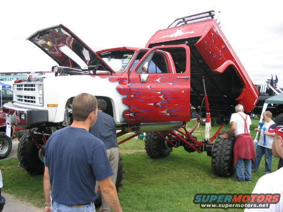 Red and white pickup truck with flame graphics, hood and bed open