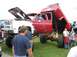 1986 Ford Bronco - This heavily modified pickup truck features custom flame paint, an open hood, and a raised bed, displayed at an outdoor event.