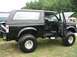 1986 Ford Bronco - A modified black Ford Bronco is displayed at an outdoor event with its doors open.