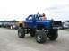 1986 Ford Bronco - A lifted pickup truck with flame decals is parked at an outdoor event with other vehicles in the background.
