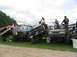 1986 Ford Bronco - Multiple modified vehicles are gathered, with people interacting with them in various ways.