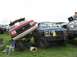1986 Ford Bronco - A man naps on the grass as two heavily modified Ford trucks are displayed at an outdoor event.