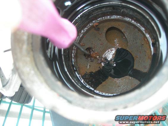 Close-up of engine part with rust and debris being cleaned