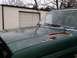 1990 Ford Bronco - A green Ford Bronco with rust on its hood is parked in front of a garage.