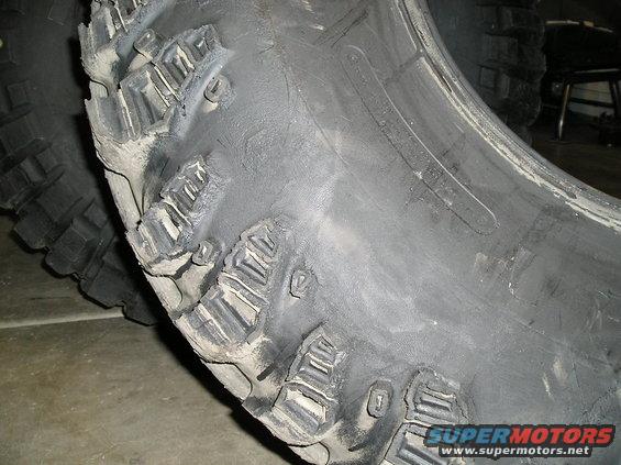 Close-up of a damaged off-road tire with torn tread blocks